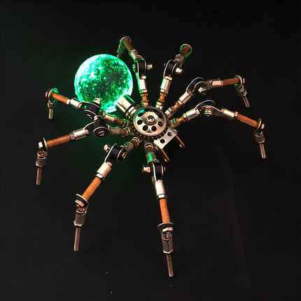 A dramatic night-view photograph of the steampunk puzzle spider model against a dark background, highlighting a brilliant bright green glowing spherical abdomen. This exquisite metal model built from precision 3D puzzle Metal Kits showcases intricate multi-jointed metallic legs and a fascinating mechanical steampunk mech aesthetic.