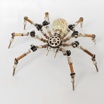 A clear top-view photograph of the steampunk puzzle spider model against a bright white background, featuring a translucent spherical abdomen filled with colorful confetti speckles. This striking metal model built from 3D puzzle Metal Kits highlights intricate multi-jointed metallic legs and an exquisite mechanical steampunk mech aesthetic.