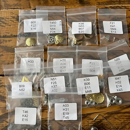 Tablefunny steampunk mechanical bee 3D metal puzzle kit parts sorted into labeled bags, including brass gears, metal plates, screws, and connectors.